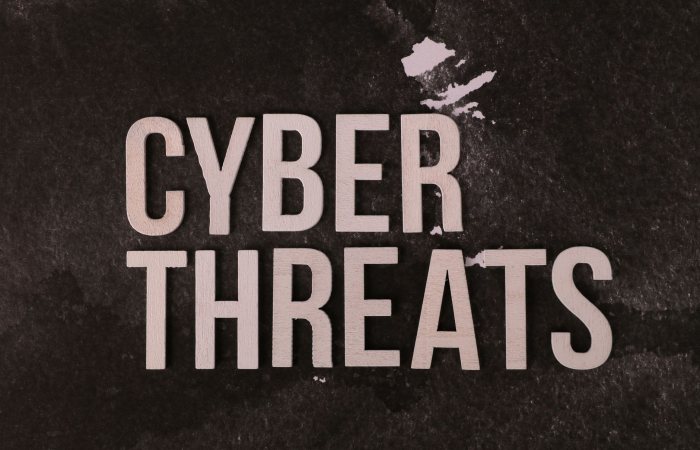 The phrase 'Cyber Threats' displayed on a textured dark background, emphasizing digital security.