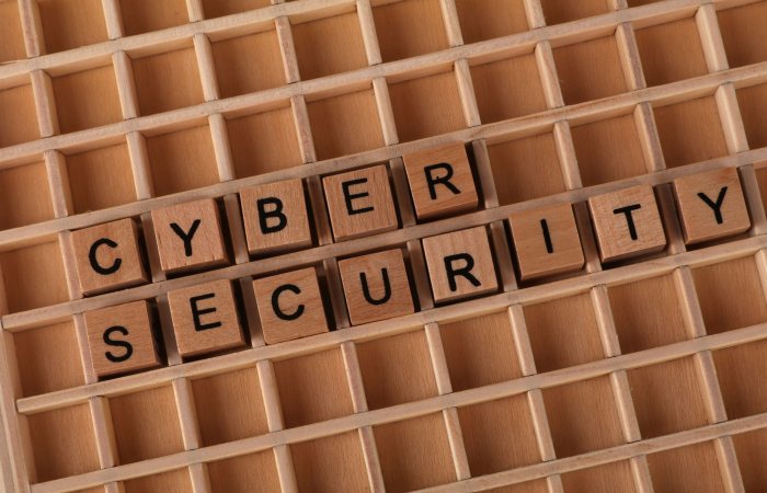 Wooden blocks spelling 'Cyber Security' on a wooden grid background.