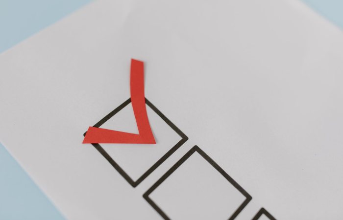 Close-up of a red check mark on a crisp white paper with black boxes, symbolizing completion.