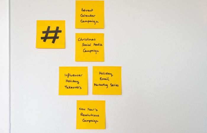 Organized yellow sticky notes on a white wall for holiday marketing strategies.