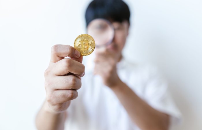 A person holds a bitcoin coin, highlighting its importance and value.