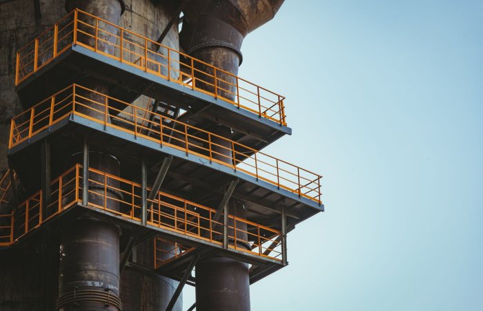 Close-up view of industrial metal balconies and pipes against a clear sky.