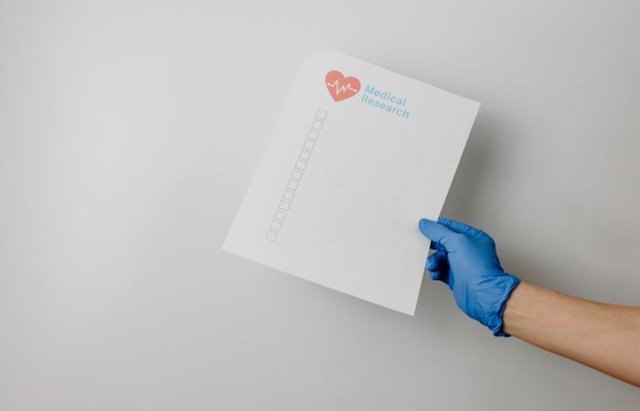 A gloved hand holding a paper titled 'Medical Research' with checkboxes.