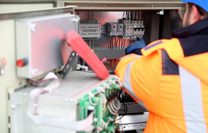 Professional engineer inspecting industrial electrical circuit board, ensuring safety standards.