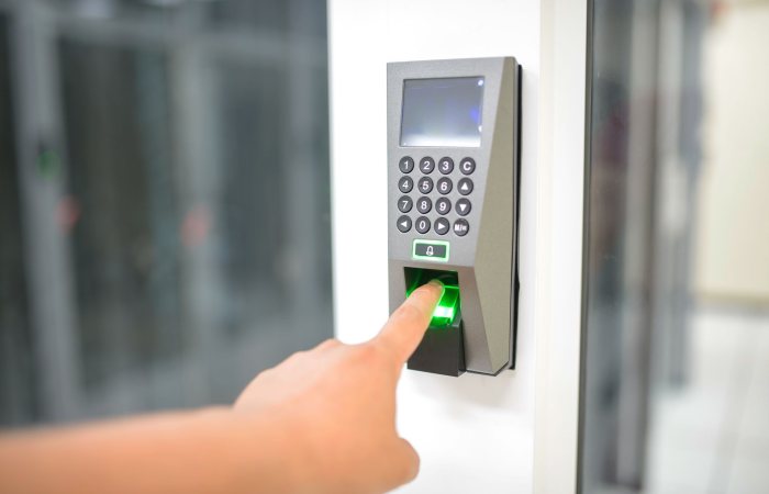 A person uses a fingerprint scanner for secure entry in a business setting.